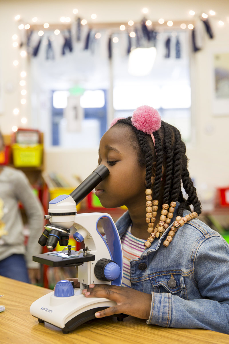 Young girl looking into a microscope 