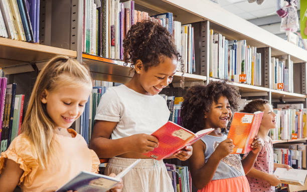Four young children holding books while smiling